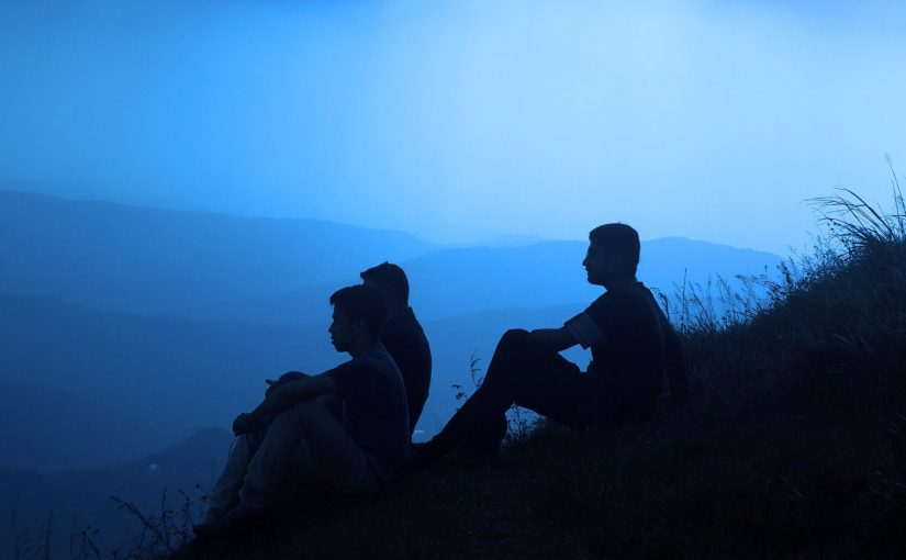 silhouette of group on the side of a hill at dusk